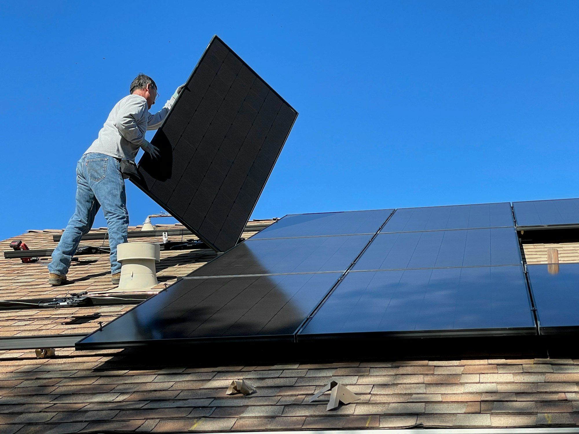 An installer positioning a solar panel on a roof